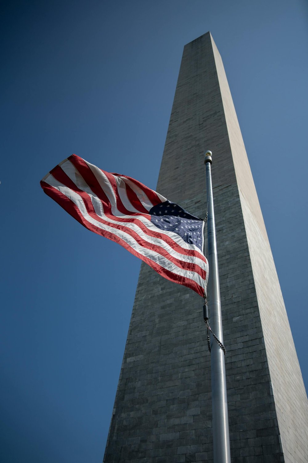 US National Flag on a flagpole in front of capital Monument