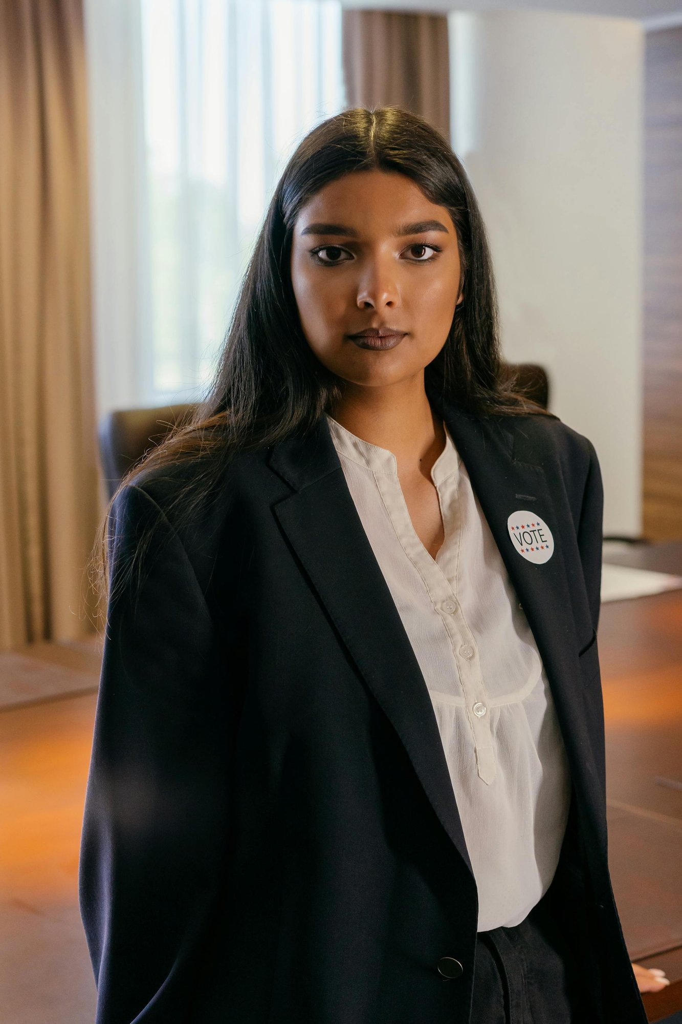 woman in black blazer leaning on wooden table. woman in black blazer leaning on wooden table.
